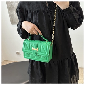 Detail of bright green quilted crossbody bag with golden chain and metallic buckle