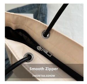 Detailed macro view of smooth silver metal zipper and black handles on canvas tote bag