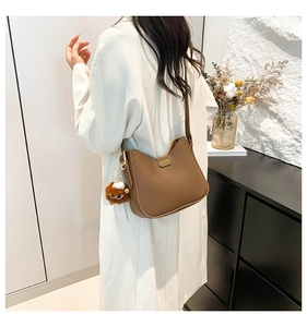Detail of brown leather bucket bag with fashion metal plate and lion head plush charm