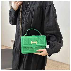 Close-up of bright green quilted crossbody bag with gold chain and metal buckle detail