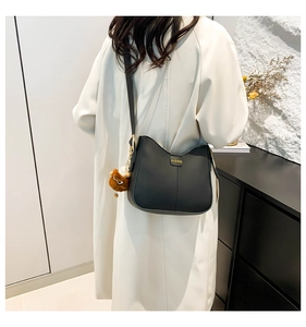 Detail of black matte PU leather crossbody bag with FASHION logo and plush charm accessory