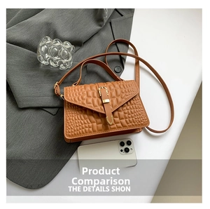 Brown crocodile pattern crossbody bag with gold buckle next to a smartphone for size