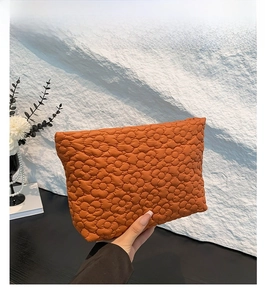Detail of orange quilted handbag showing clover textured fabric and soft padded material