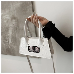 Detail of white crocodile textured handbag featuring embroidered AMIEBO logo patch