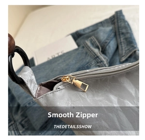 Detail shot of smooth golden metal zipper on silver metallic texture underarm bag