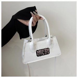 Detail of white crocodile pattern handbag featuring a ZMIEBO embroidered patch and handle