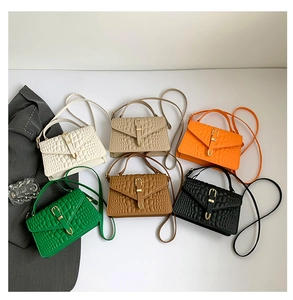 Flat lay of six crocodile embossed crossbody bags in white beige orange green brown and black