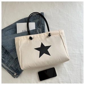 Detail of beige quilted tote bag with black star pattern and durable shoulder straps