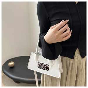 Close-up of white crocodile pattern crossbody bag featuring ZMIEBO embroidery patch