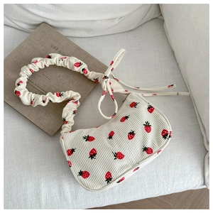 Detail of strawberry print on corduroy shoulder bag with scrunchie strap and bow