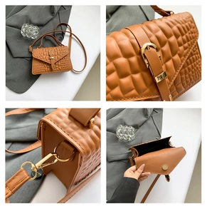 Detail of brown faux leather handbag showing crocodile texture and gold hardware