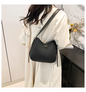 Detail of minimalist black leather shoulder bag with gold embossed FASHION lettering logo