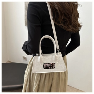 Close-up of white crocodile pattern crossbody bag with brand embroidery on street model