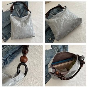 Detail view of silver tote bag with wooden bead strap and spacious fabric interior