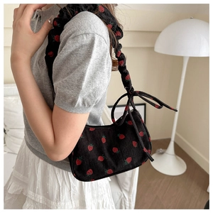 Detail of strawberry print corduroy bag with ruffled shoulder strap and bow accent