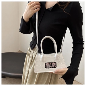 Detailed view of white crocodile texture crossbody bag featuring a pink ZMIEBO logo patch