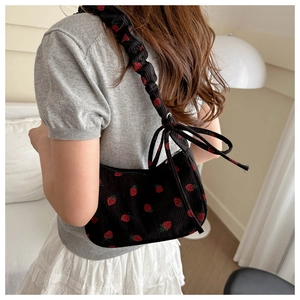 Detail of strawberry print corduroy underarm bag with ruffled shoulder strap and bow