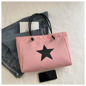 Flat lay of pink canvas tote bag with black star print, styled with casual accessories