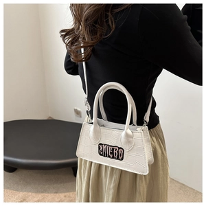 Model wearing a white crocodile-textured mini bag with a ZMIEBO letter patch