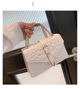 Detail of white crocodile pattern shoulder bag with golden buckle and textured finish