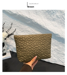 Detail of a brown quilted clutch featuring an embossed 3D floral texture and soft finish