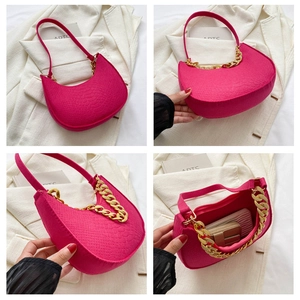 Detail van fuchsia halve maan tas met krokodillenpatroon en dikke gouden ketting