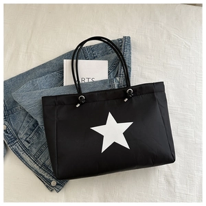 Detail of black canvas tote bag showing white star print and silver drawstring buckle