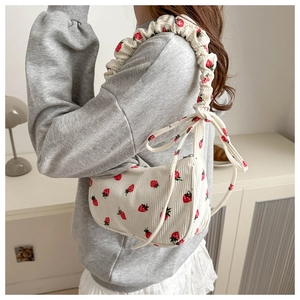 Detail of corduroy shoulder bag featuring strawberry prints and ruffled bubble strap