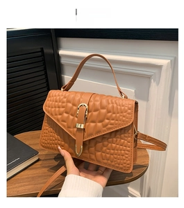 Detail of a brown crocodile pattern handbag featuring a gold horse-stirrup metal buckle