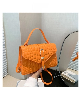 Detail of orange crocodile pattern small square handbag with golden metallic buckle