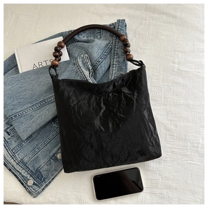 Detail view of black wrinkled texture handbag with decorative wooden bead handles