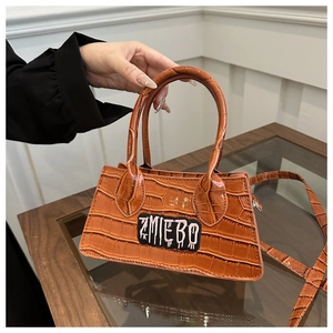 Detail of orange crocodile texture leather bag with ZMIEBO embroidery and chain strap