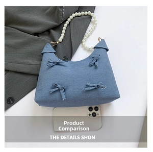 Detail of light blue denim tote with bow decor and pearl handle next to a smartphone