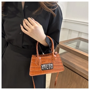 Chic brown crocodile pattern handbag with ZMIEBO logo held by model in indoor setting