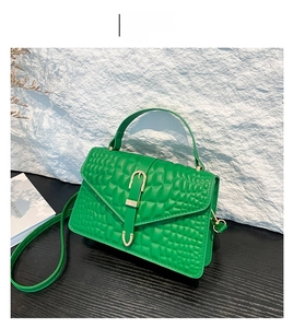 Detail of green crocodile texture handbag with gold metal clasp and envelope flap