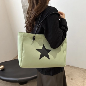 Mint green tote bag with black star print and slim straps shown on a female model