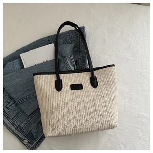 Close-up of a woven straw tote bag with black contrast handles and top view scene layout