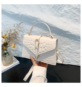 Detail of cream crocodile embossed handbag with gold buckle and adjustable strap