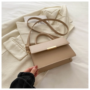 Detail of khaki textured crossbody bag with gold metal buckle and leather handle
