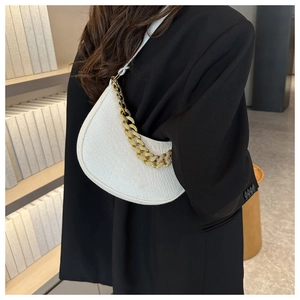 Detail van witte halve maan tas met krokodillenprint en grove gouden ketting