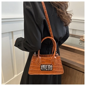 Close-up of brown crocodile embossed texture and graffiti patch on elegant handbag