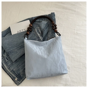 Detail of light blue pleated velvet bag with retro wooden bead handle and metal ring