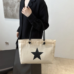 Minimalist beige tote bag with black star print and knot shoulder strap for daily commuting