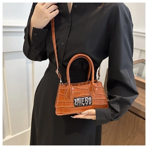 Detail of a brown croc-effect mini bag with ZMIEBO embroidery and shoulder strap