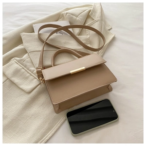 Detail of minimalist beige PU leather handbag with gold buckle and adjustable strap