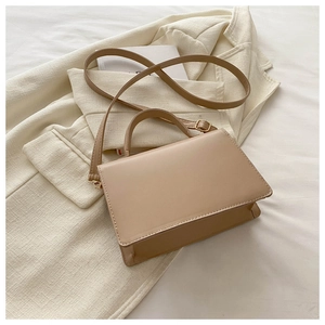 Detail of minimalist beige faux leather handbag with soft golden hardware and top handle