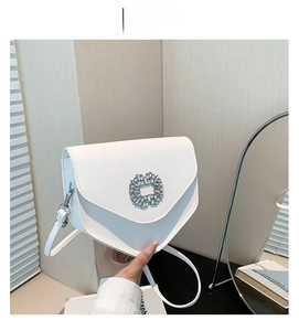 Détail du sac bandoulière blanc en cuir avec boucle florale en cristal et rabat en V chic