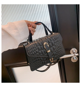Close-up of black crocodile pattern handbag featuring a gold U-shaped buckle and fine strap
