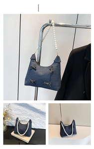Detail of dark blue denim underarm bag with pearl chain handle and bow accents