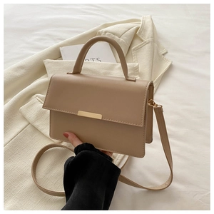 Detail of beige PU leather handbag with golden buckle and textured crossbody strap